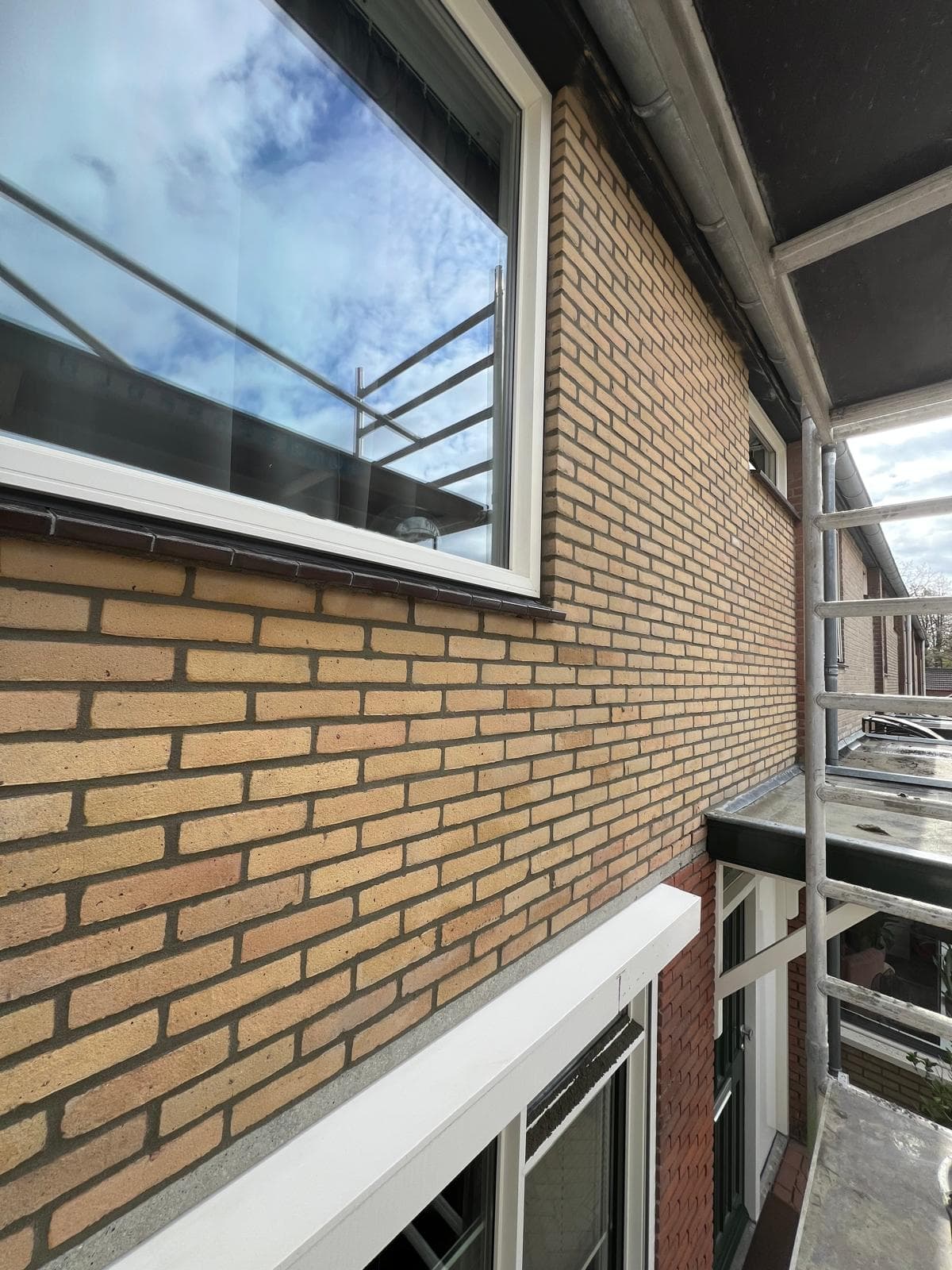 Vers voegwerk op bakstenen muur vanuit steiger, vakkundig afgewerkt